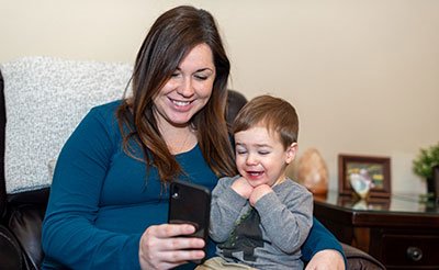 mother holding toddler during telemedicine call
