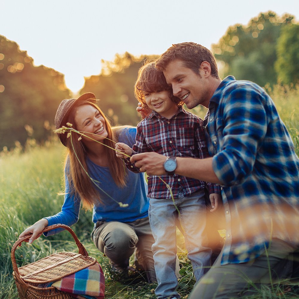 Mother, father, and son enjoying a picnic date out in a field, representing good asthma care