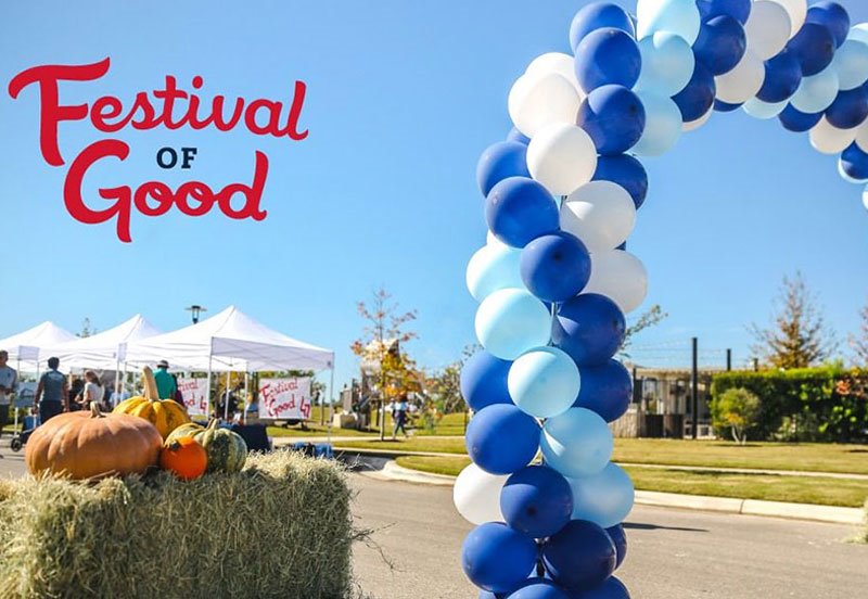 Event setup at the Festival of Good featuring a blue and white balloon arch, pumpkins, and booths