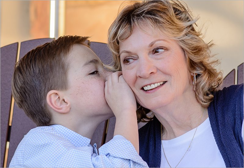 Grandmother listening to her grandson whisper in her ear
