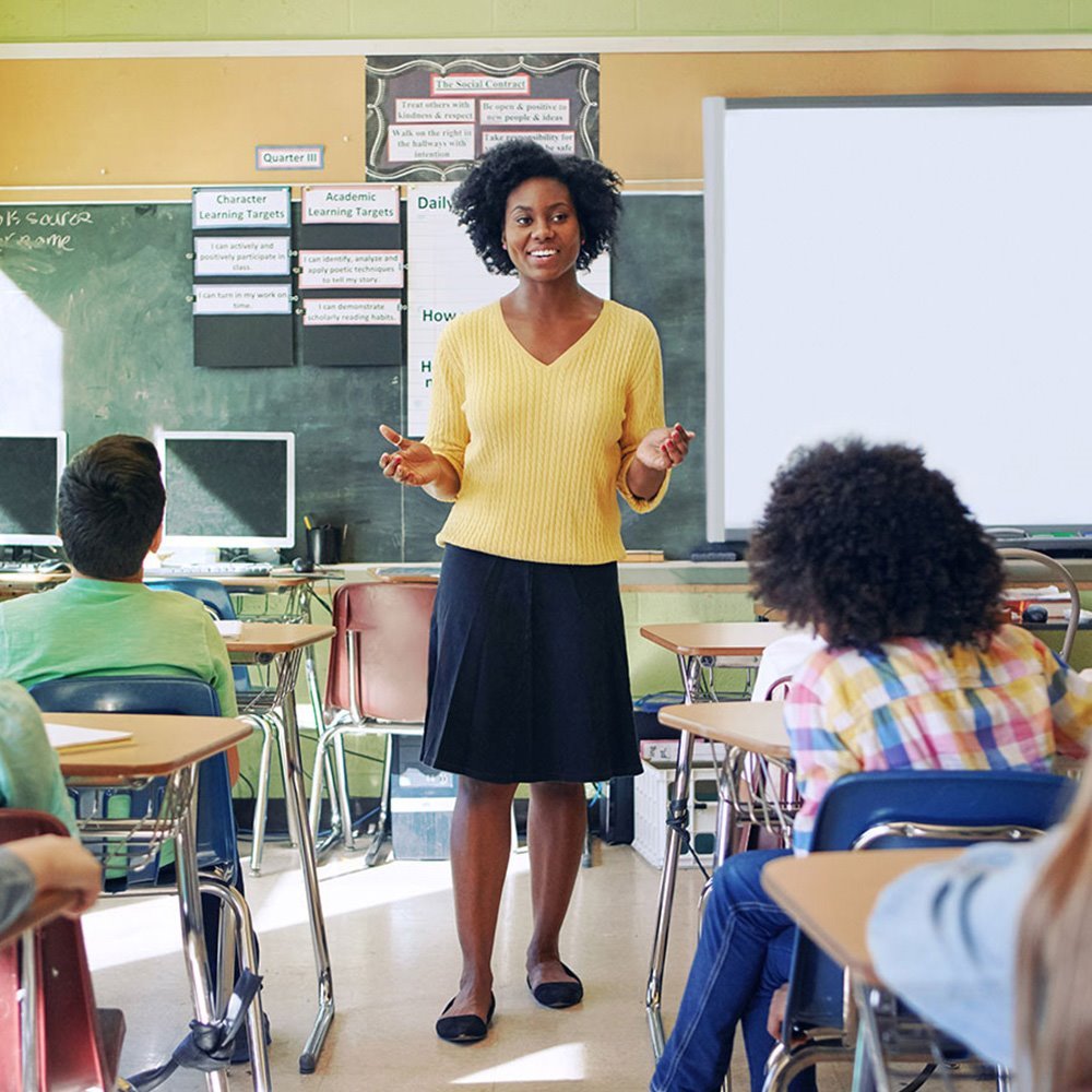 Teacher giving a lesson in a classroom full of students, representing good health following an annual checkup