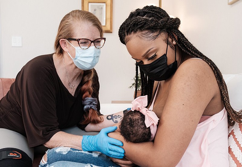 Lactation consultant helping a new mom breastfeed her baby