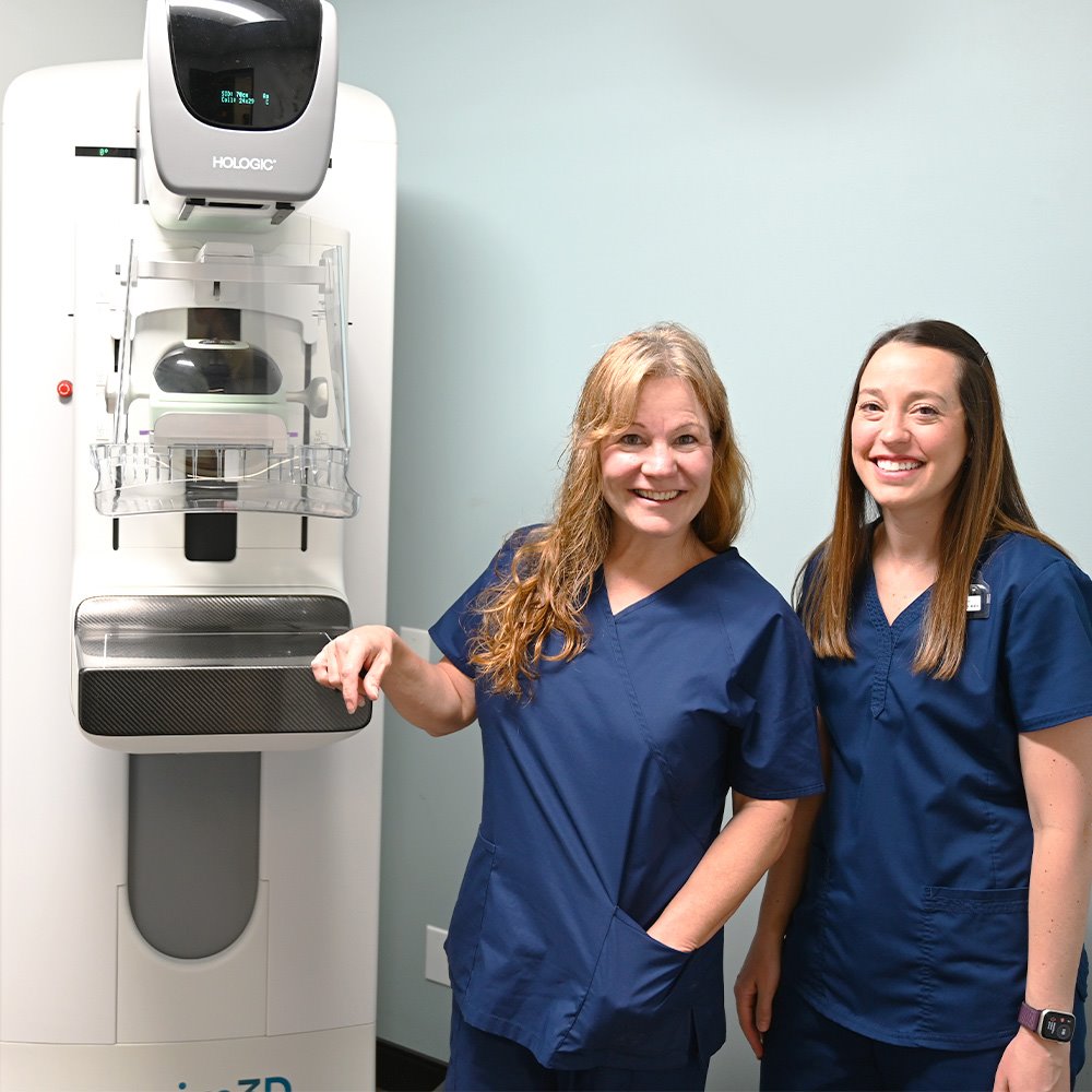 Two ARC mammography technicians next to a mammography machine at ARC