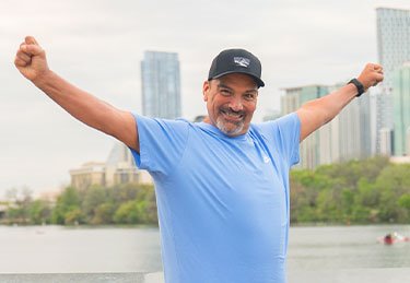 ARC patient stretching out his hands, representing happiness and success with the ARC Healthiness Program, while at Lady Bird Lake in Austin