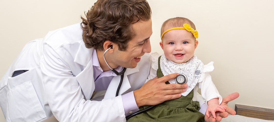 ARC pediatrician using a stethoscope to examine a baby patient during a well-check exam