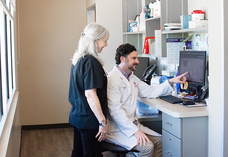 Austin Regional Clinic Doctor looking at a computer with a nurse
