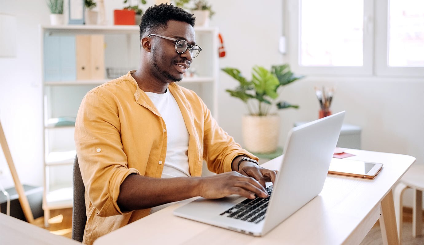 photo of smiling man using laptop computer