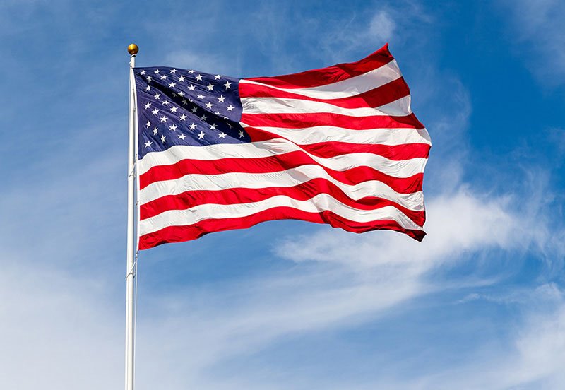 An American flag waving at the top of a flagpole, celebrating Independence Day