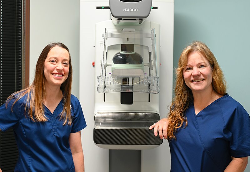 Two ARC mammography technicians next to a mammography machine at ARC