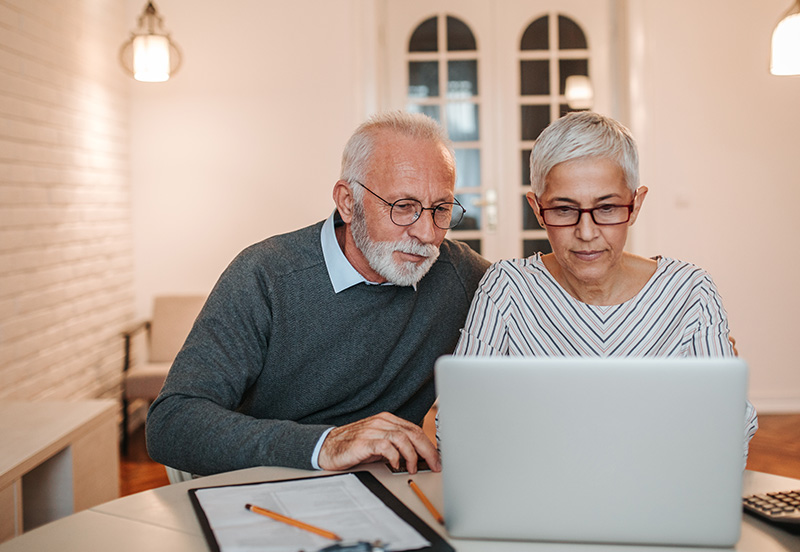 An older couple using a laptop for open enrollment