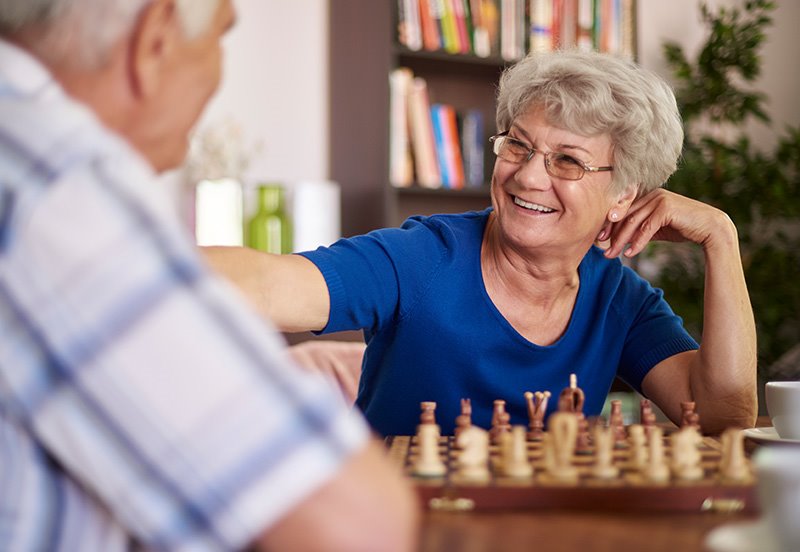 Older couple enjoying a game of chess, representing good mental and physical activity—reminder to schedule your Annual Medicare Wellness Visit