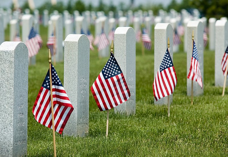 Cemetery with American flags in front of every memorial stone, signifying Memorial Day