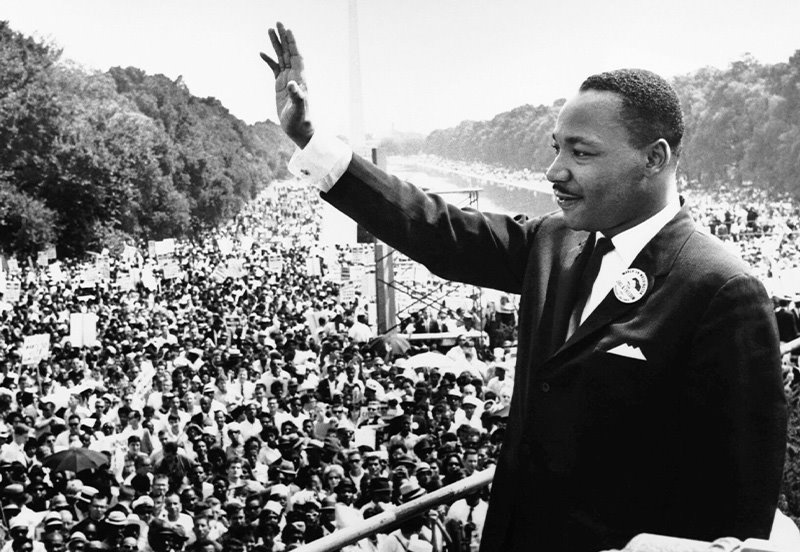 Dr. Martin Luther King, Jr. waving at the crowd during his speech at the Lincoln Memorial, overlooking the National Mall towards the Washington Monument