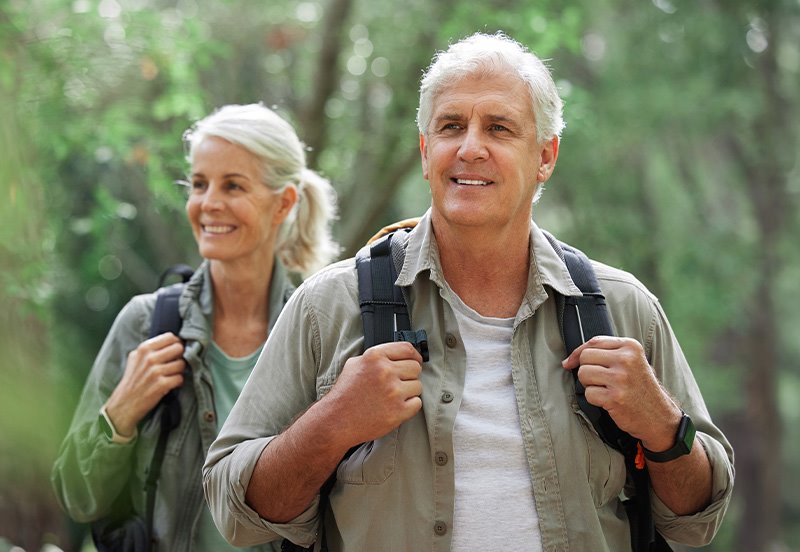 Older couple enjoying a hike outdoors, highlighting good mobility, strength, and orthopedic wellness