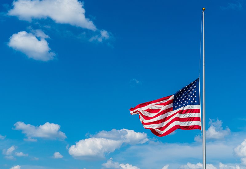 American flag being flown at half-staff, representing Patriot Day, the National Day of Service and Remembrance